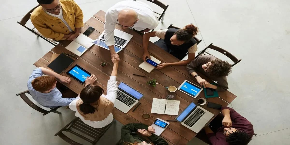 Team collaborating around a conference table with laptops and tablets